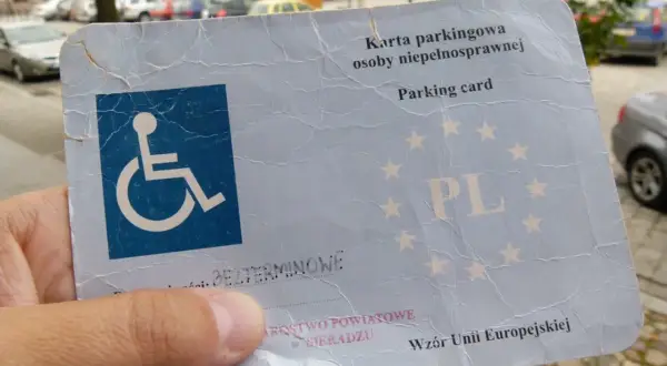 Karta parkingowa dla niepełnosprawnych z symbolem wózka inwalidzkiego i gwiazdkami UE.