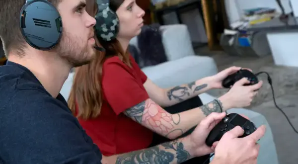 Ein Paar spielt konzentriert auf der PS4, bis die PS4 abgeschaltet wird.