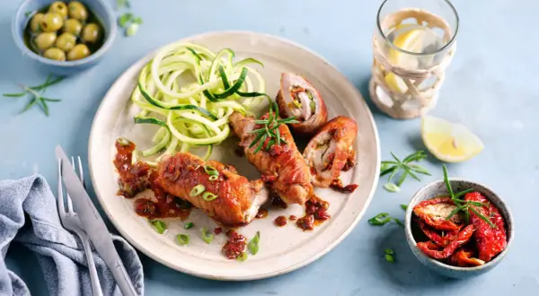 Herzhafte involtini vom Kalb mit Zucchini-Spaghetti und einer würzigen Tomatensauce, garniert mit Rosmarin.