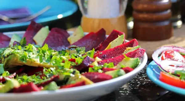 Pyszne carpaccio z buraka z awokado i świeżą natką pietruszki, doprawione pieprzem.