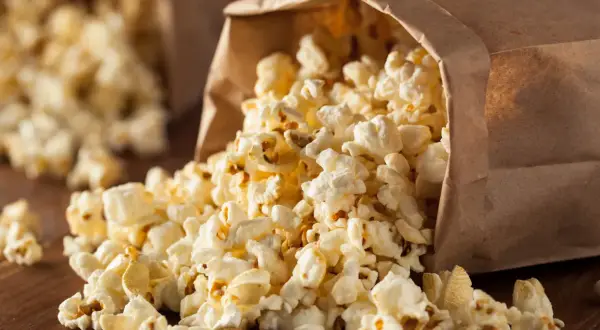 Góra popcornu wysypuje się z papierowej torby. Czy popcorn jest zdrowy? To zależy od sposobu przygotowania.