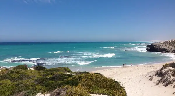 Türkisblaues Meer und Sanddünen im De Hoop Nature Reserve. Kleine Figuren genießen den Strand.