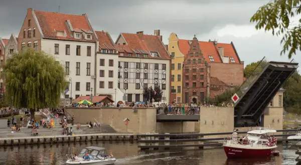Widok na starówkę Elbląg z kanałem, podniesionym mostem zwodzonym i łodziami.