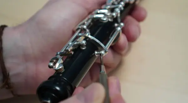 Hände justieren die Mechanik einer Oboe. Ein Schraubenzieher wird angesetzt. Der Weg zum Oboe lernen beginnt oft mit der Pflege des Instruments.