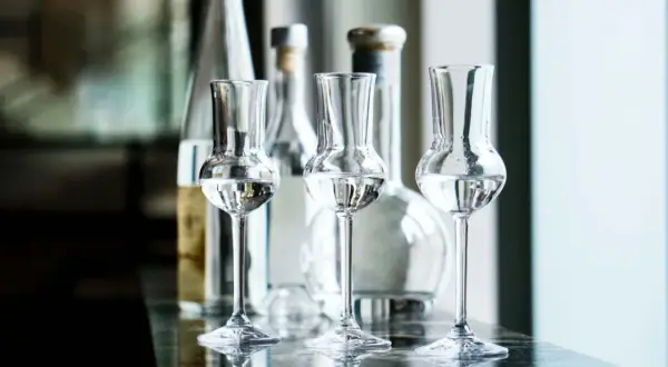 Trzy kieliszki z przezroczystym płynem, idealne do degustacji grappy. Co to jest grappa? To włoski destylat z wytłoków winogron.