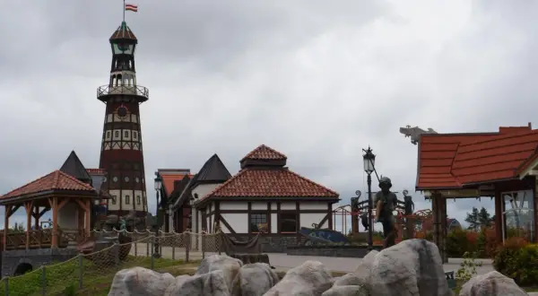 Wesołe miasteczko Hossoland kiedy otwarcie? Widok na latarnię morską, domki w stylu portowym i rzeźby.