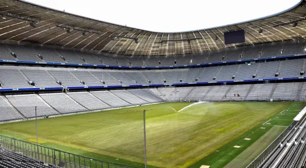 Pusta Allianz Arena, z zieloną murawą i trybunami czekającymi na kibiców.