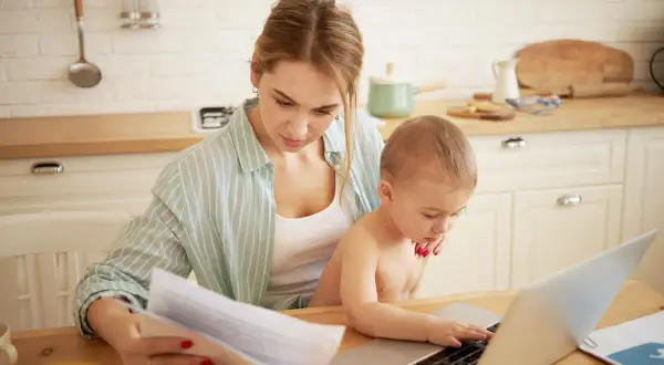 Mama pracuje przy laptopie, a dziecko próbuje jej pomóc. To codzienność, gdy macierzyński ile trwa.