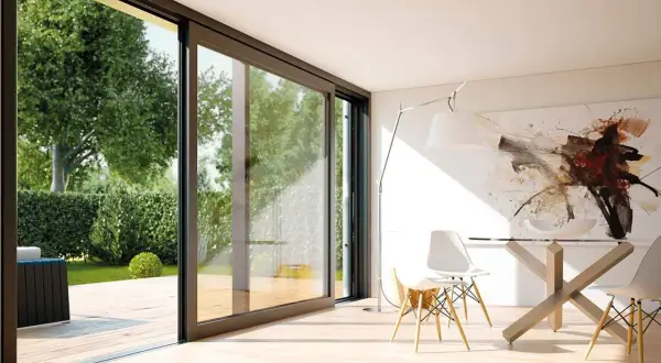 Amplias ventanas correderas modernas conectan un comedor minimalista con un jardín exuberante, mostrando diferentes tipos de ventanas modernas.