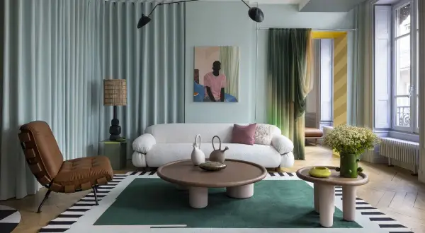 Salotto con divano bianco bouclé, poltrona in pelle, tappeto geometrico e lampada da terra, in un audace stile massimalista.
