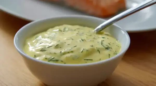 Krämig sås till lax, med dill och andra örter, serverad i en vit skål. En perfekt sås till din laxrätt.