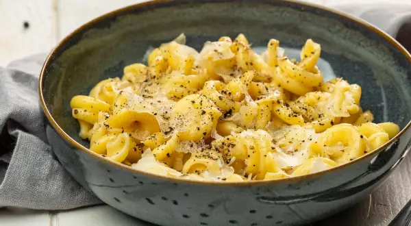 Cacio e pepe: eine Schüssel mit cremiger Pasta, bestreut mit frisch geriebenem Pecorino Romano und schwarzem Pfeffer.