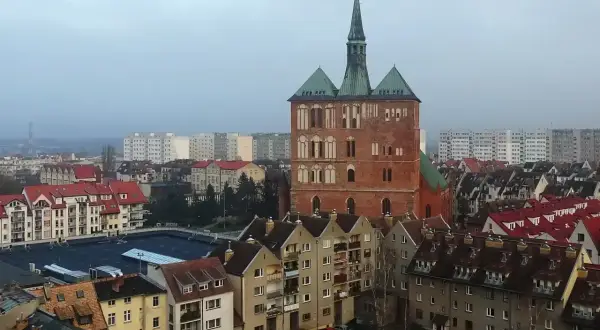 Widok na ceglaną wieżę kościoła i zabudowania miejskie Kołobrzegu.