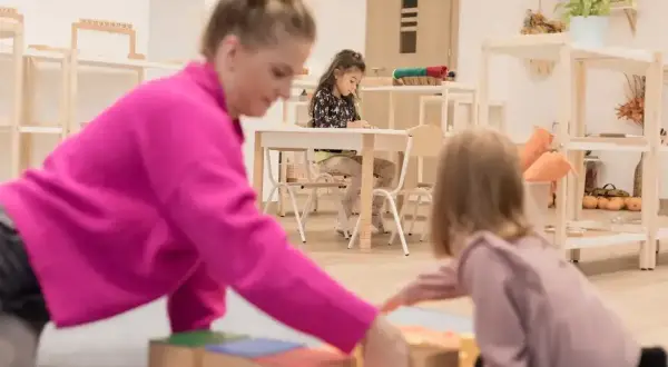 Nauczycielka pokazuje dzieciom, co to montessori, podczas zabawy klockami.