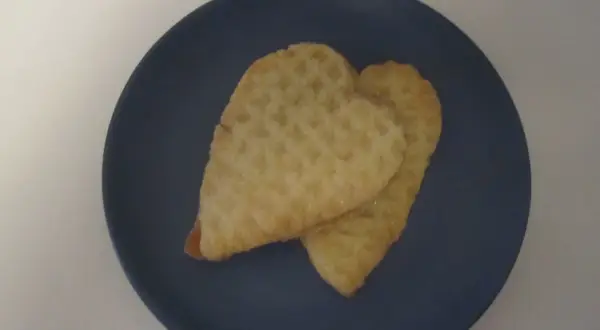 Två hjärtformade kex med socker på en mörkblå tallrik. Perfekta för parisare recept.