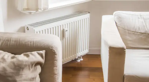 Gemütliche, helle Couch vor einer weißen Heizung, bereit für entspannte Stunden.