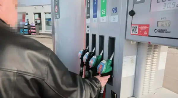 Mężczyzna w czarnej kurtce sięga po dystrybutor z napisem "verva diesel" na stacji paliw.