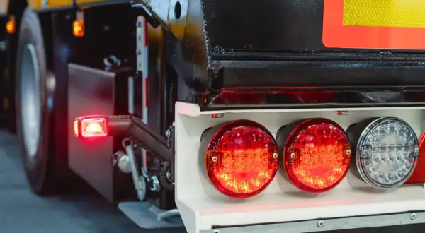 Feux arrière de camion, dont un clignotant rouge allumé. Le système de frein moteur est essentiel pour la sécurité.