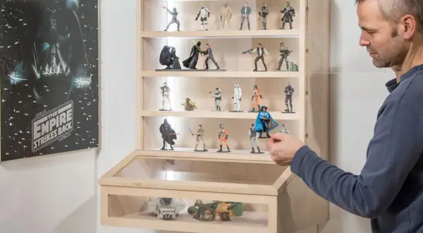 Mann arrangiert Star Wars Figuren in einer selbstgebauten Acryl Vitrine.