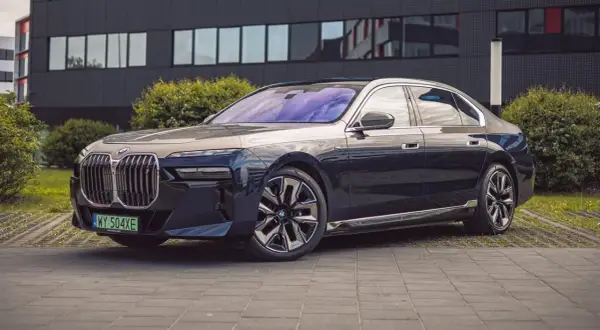 Eleganckie BMW i7 w ciemnym kolorze prezentuje się luksusowo przed nowoczesnym budynkiem.