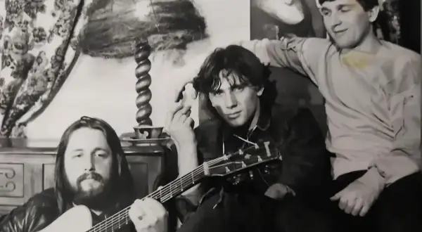 Trzech muzyków zespołu Universe pozuje z gitarami w przytulnym wnętrzu.
