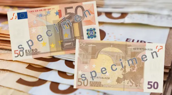 Banknoty 50 euro, oznaczone jako "specimen", leżą na stosie innych banknotów.