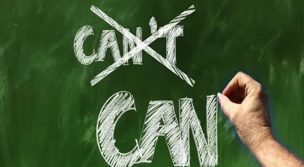 Ręka pisze kredą na tablicy "CAN", przekreślając "CAN'T". Koniec z postawą osoby pasywnej!