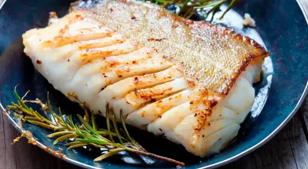 Zdrowa ryba zębacz, soczysty filet z chrupiącą skórką, podany z rozmarynem na talerzu.