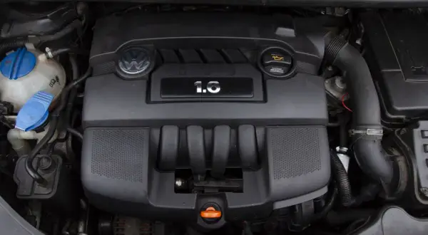 Silnik Volkswagena z oznaczeniem 1.6 MPI. Widoczny jest czarny plastikowy kolektor, logo VW i zbiornik płynu chłodniczego.