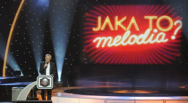 Prowadzący w studiu "Jaka to melodia?" z mikrofonem. Zastanawiasz się, ile kosztuje minuta reklamy w trakcie trwania tego programu?