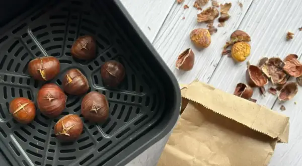 Châtaignes grillées dans un air fryer, prêtes à être dégustées. Les peaux éparpillées témoignent de leur préparation facile.