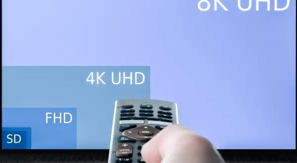 Dłoń trzymająca pilot do telewizora, na ekranie w **hd format** widać porównanie rozdzielczości: 8K UHD, 4K UHD, FHD i SD.