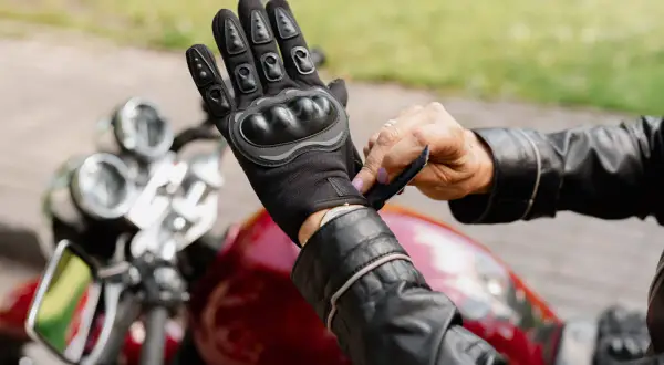 Motocyklista zapina rękawicę z ochraniaczami. Różne rodzaje ochraniaczy zapewniają bezpieczeństwo.