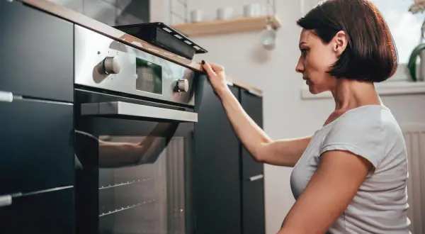 Donna controlla il display del suo forno a gas o elettrico prima di iniziare a cucinare.