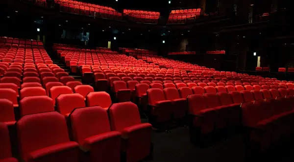 Puste czerwone fotele w teatrze, czekające na widzów. Zastanawiasz się, ile trwa spektakl w teatrze?