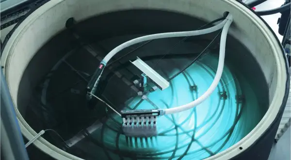 Ein großer Tank mit Wasser, Rohren und einem Gerät zur Eisbildung. Hier wird ein **Eisspeicher selber bauen**-Projekt umgesetzt.