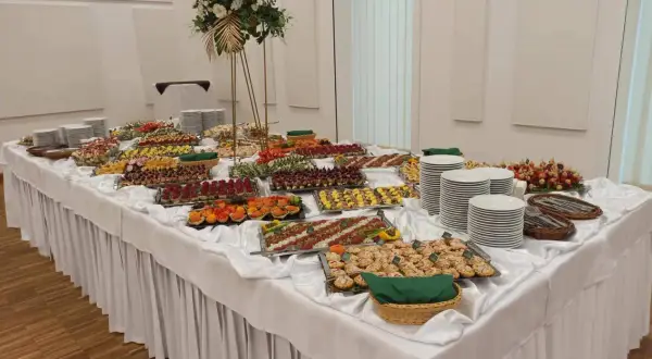 Stół z bogatym cateringiem: przekąski, sałatki, przystawki, talerze i dekoracje.
