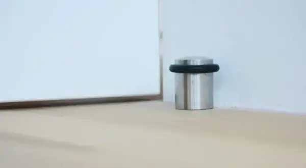 Elegancki, metalowy odbojnik z czarną gumką chroni ścianę przed uderzeniem drzwi.