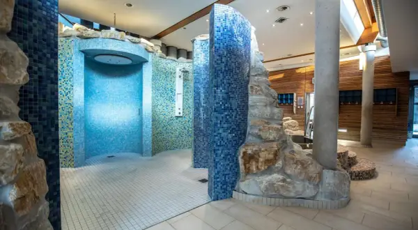 Moderne Duschen mit Mosaikfliesen und Felsenelementen in der Therme Regensburg laden zum Entspannen ein.