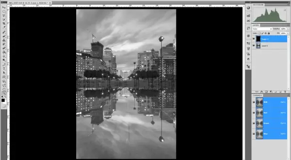 Interface Photoshop : une image de ville en noir et blanc avec ses reflets dans l'eau. Le calque "Layer 1" est sélectionné, prêt à mettre un calque en noir et blanc.