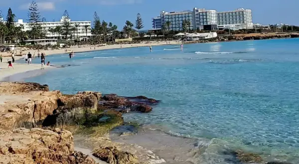 Słoneczny dzień na plaży Ayia Napa. Turkusowa woda, piaszczysty brzeg i hotele w tle.