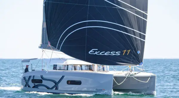 Catamarano Excess 11 con vela nera che naviga in mare aperto.
