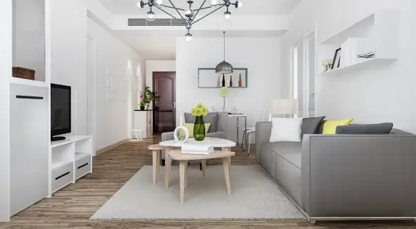 Nowoczesny salon z szarą kanapą i stolikami kawowymi. Idealne miejsce na pkd wynajem krótkoterminowy.