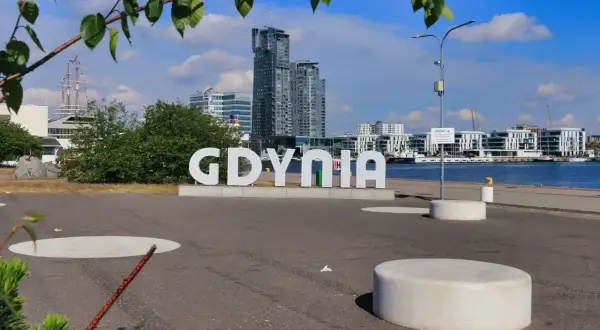 Idealny weekend w Trójmieście zaczyna się od napisu GDYNIA. W tle nowoczesna architektura i żaglowiec.
