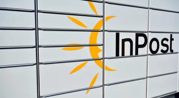 Zbliżenie na białą paczkomat InPost z żółtym logo i czarnym napisem.