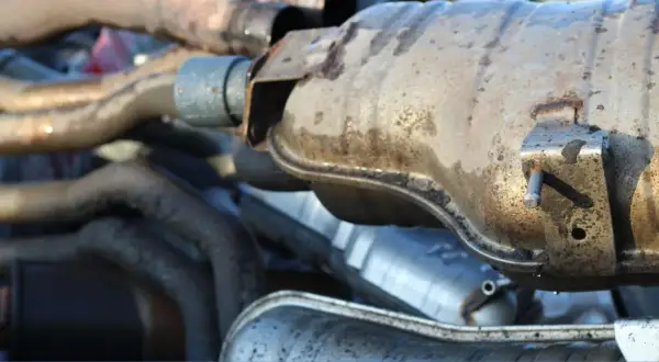 Gros plan sur des pièces de système d'échappement de voiture, dont un catalyseur potentiellement bouché, un symptôme courant sur les moteurs diesel.