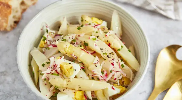 Schüssel mit Spargelsalat mit Ei, Radieschen und Schnittlauch, dazu ein Stück Baguette.