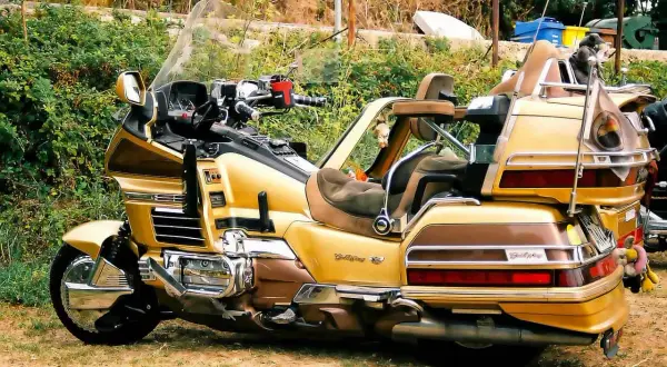 Złoty motocykl turystyczny z dużym bagażnikiem i wygodnymi siedzeniami.