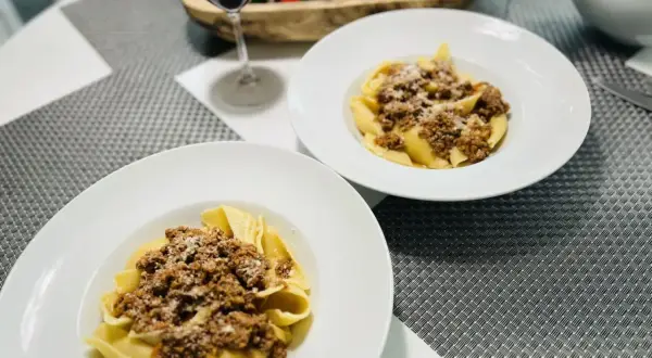 Deux assiettes de pâtes conchiglioni garnies d'une généreuse sauce bolognaise, prêtes à être dégustées avec un verre de vin rouge.