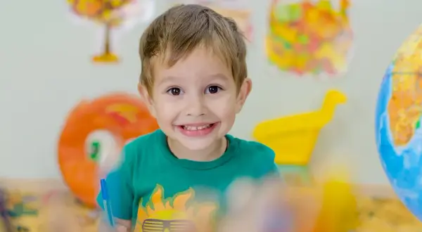 Niño sonriente con camiseta verde, aprendiendo sobre el mundo. Fomenta la autoestima en niños de 6 a 12 años.